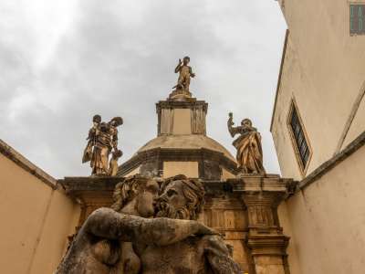 Oltre la vasca in alto intravediamo altre statue: un Nettuno su un pesce, affiancato dalle raffigurazioni della Maternit� e della Fede